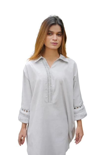 Woman wearing a light gray kurta with intricate detailing in an outdoor setting.