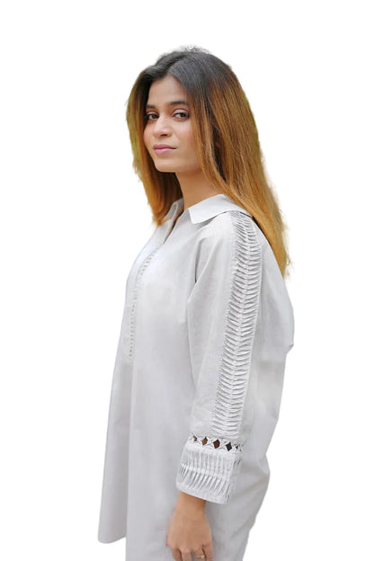 Woman wearing a white outfit with intricate detailing in an outdoor setting