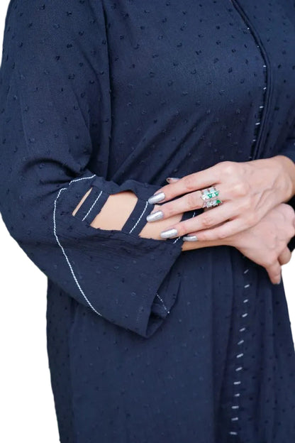 Person wearing a navy black long-sleeve top with cut-out design on the arm, holding a phone.